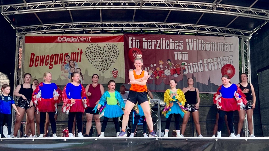Viele Kinder tanzen gemeinsam Zumba auf einer Bühne während der Veranstaltung „Erfurt bewegt sich“. Die Teilnehmenden führen fröhlich choreografierte Bewegungen vor und sorgen für eine lebendige Atmosphäre.